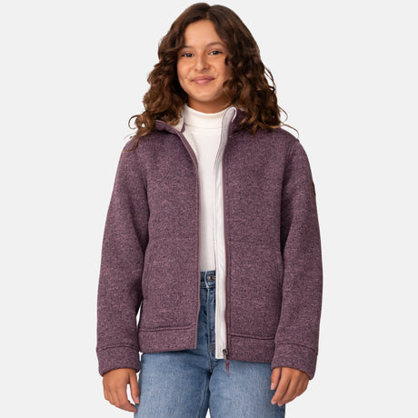 [Model is wearing size M.] Girl wearing the Free Country Girls' Mountain Fleece Jacket in textured purple, layered over a white shirt and blue jeans, smiling in a neutral-colored indoor setting.