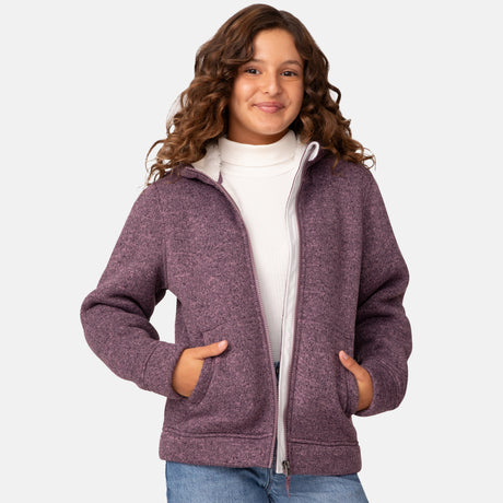 [Model is wearing size M.] Girl wearing the Free Country Girls' Mountain Fleece Jacket in textured purple, layered over a white shirt and blue jeans, smiling in a neutral-colored indoor setting.