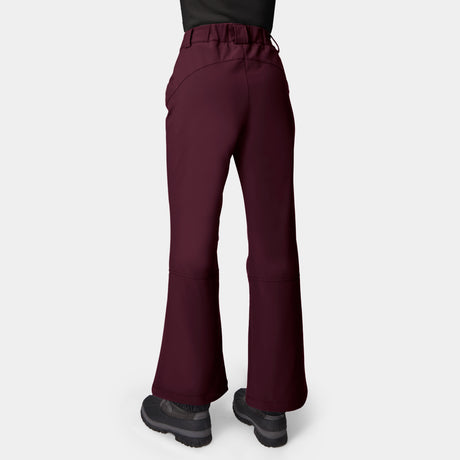 Woman wearing Free Country Women’s Stormlite Super Softshell® Ski Pant in maroon with black shoes, shown from the back against a plain white background.