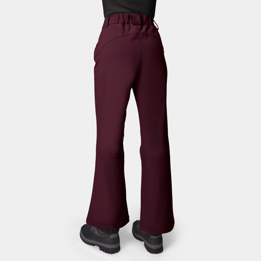 Woman wearing Free Country Women’s Stormlite Super Softshell® Ski Pant in maroon with black shoes, shown from the back against a plain white background.