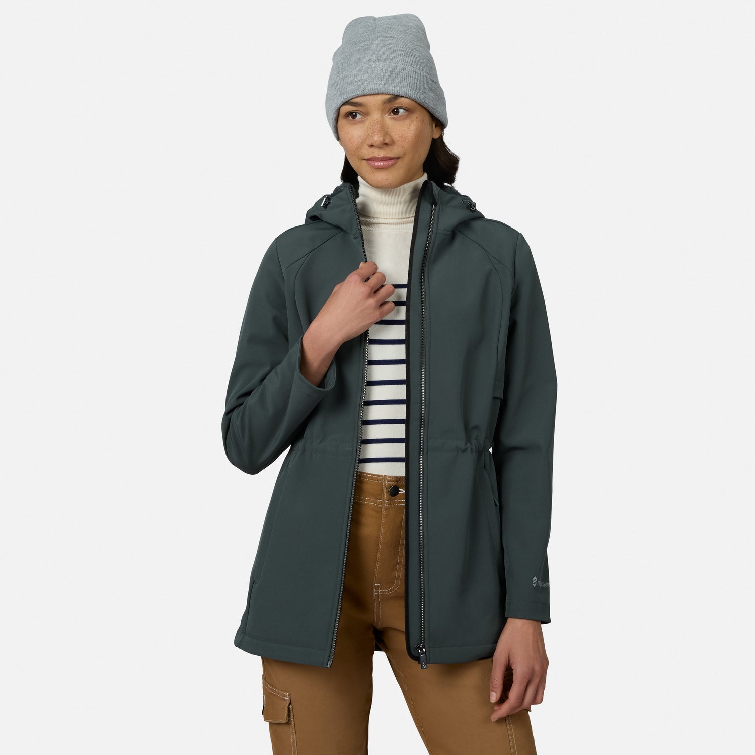 [Model is wearing size S.] A woman wearing a dark slate green hooded jacket, a light gray beanie, a white turtleneck, a navy and white striped shirt, and brown pants, standing against a light gray studio background.