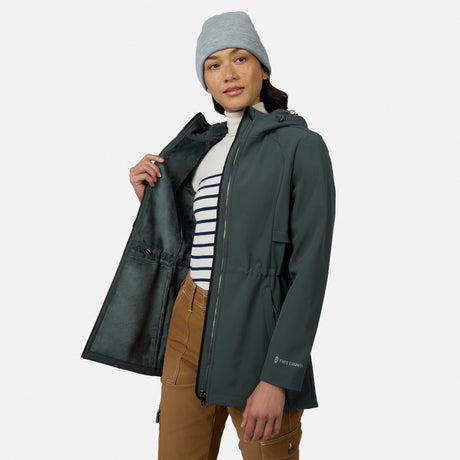 [Model is wearing size S.] A woman wearing a dark gray hooded waterproof jacket, a gray beanie, a white and navy striped turtleneck, and brown pants, shown against a light gray studio background.