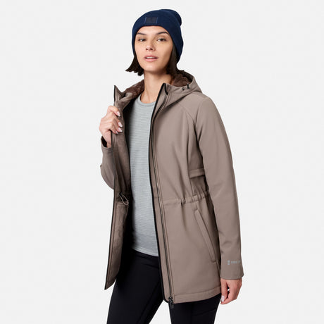 [Model is wearing size S.] A woman modeling a hooded insulated jacket in taupe-brown, worn over a light gray ribbed top and black pants, with a navy beanie. The jacket has a brown faux-fur lined hood and a drawcord waist, shown against a light gray studio background.