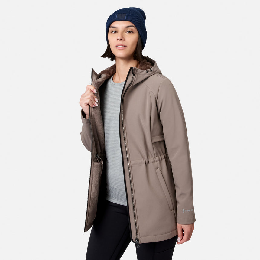 [Model is wearing size S.] A woman modeling a hooded insulated jacket in taupe-brown, worn over a light gray ribbed top and black pants, with a navy beanie. The jacket has a brown faux-fur lined hood and a drawcord waist, shown against a light gray studio background.