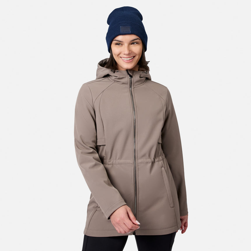 [Model is wearing size S.] A woman wearing a taupe hooded zip-up jacket and a navy blue beanie, standing against a light gray studio background.