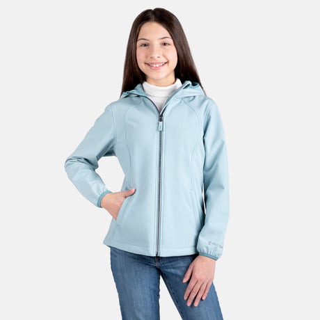 [Samantha is wearing size M.] Model wearing a Free Country light blue softshell zip-front hooded jacket with a smooth, weather-resistant finish, side pockets, and tonal stitching—layered over a white turtleneck and paired with blue jeans for a clean, casual winter look.