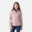 A smiling girl with long brown hair wears the Clearance Girls' Super Softshell® Jacket in Garden over a black top and blue jeans, standing against a plain light gray background.