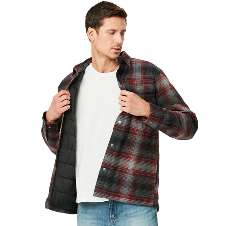 A man in a white t-shirt and blue jeans opens a Men’s FreeCycle® Utility Work Shirt by Clearance to reveal its black quilted insulated lining. He looks downward and slightly to the side.