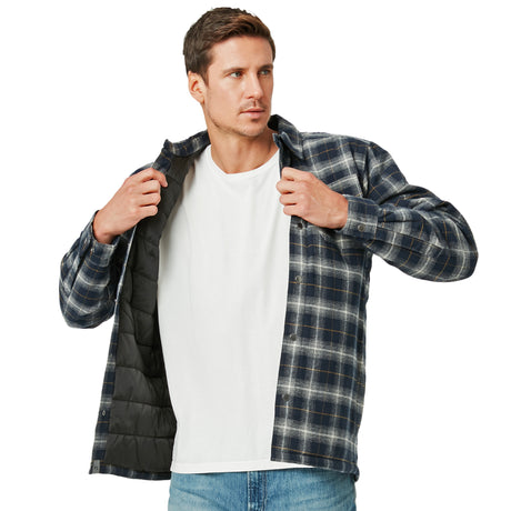 A man in blue jeans and a white tee opens a Men's FreeCycle® Utility Work Shirt by Clearance, showing its black lining. He looks to the side with a neutral expression. Made with eco-friendly REPREVE material for sustainable style.