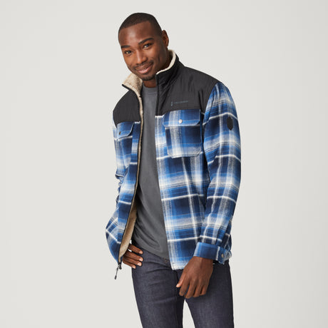[Model is wearing a size Medium.] Man wearing Free Country Men's Woodsman Work Jacket in blue and white plaid with a full front zipper opening, soft lining, and recycled polyester filling, light grey background. Perfect men’s jacket for fall weather.