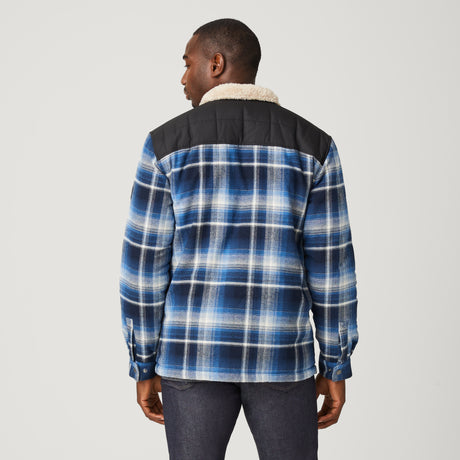 [Model is wearing a size Medium.] Man wearing Free Country Men's Woodsman Work Jacket in blue and white plaid with a full front zipper opening, soft lining, and recycled polyester filling, light grey background. Perfect men’s jacket for fall weather.