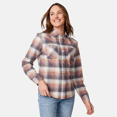 [Model is wearing size S.] A woman modeling a long-sleeve plaid button-up shirt in muted tones of brown, beige, and dusty pink, paired with blue jeans against a light gray studio background.