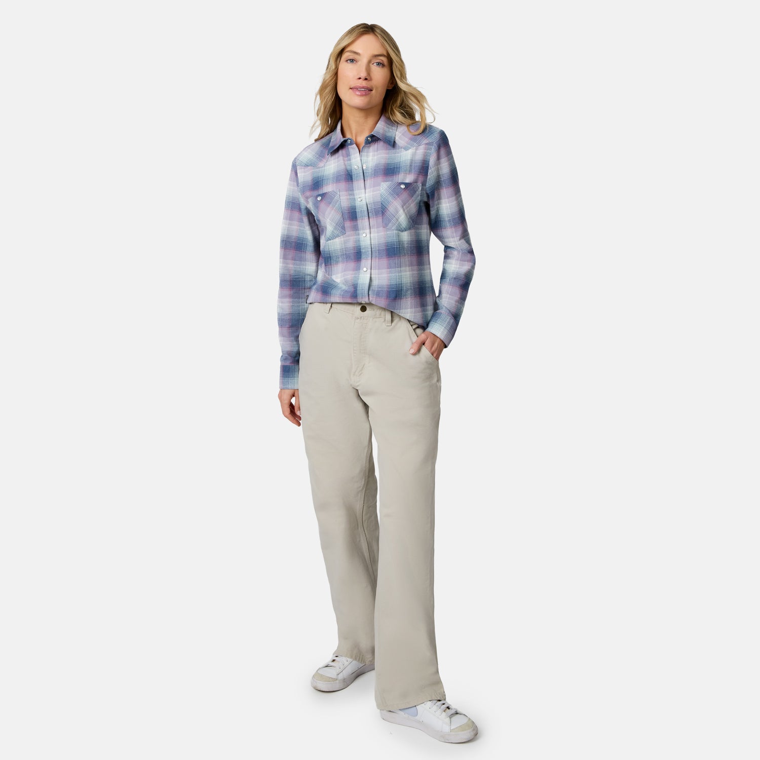 [Model is wearing size S.] A woman modeling a long-sleeve button-up plaid shirt in shades of purple, blue, and white, paired with beige straight-leg pants and white sneakers, against a light gray studio background.