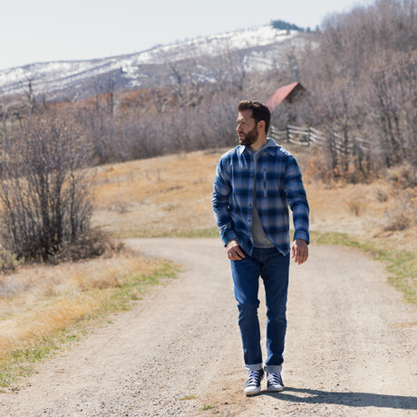 Man walking on a dirt road with mountains in the background