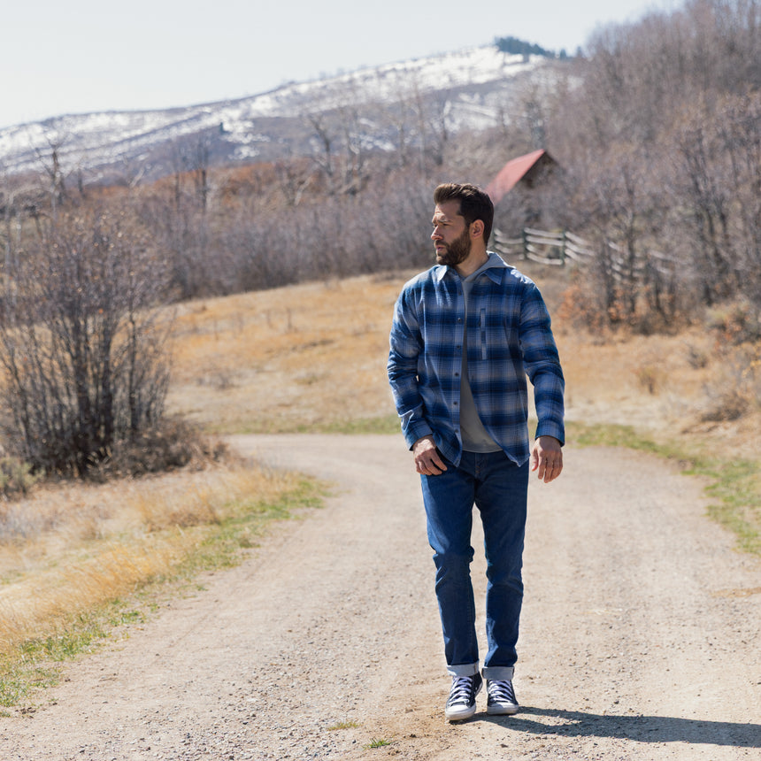 Man walking on a dirt road with mountains in the background
