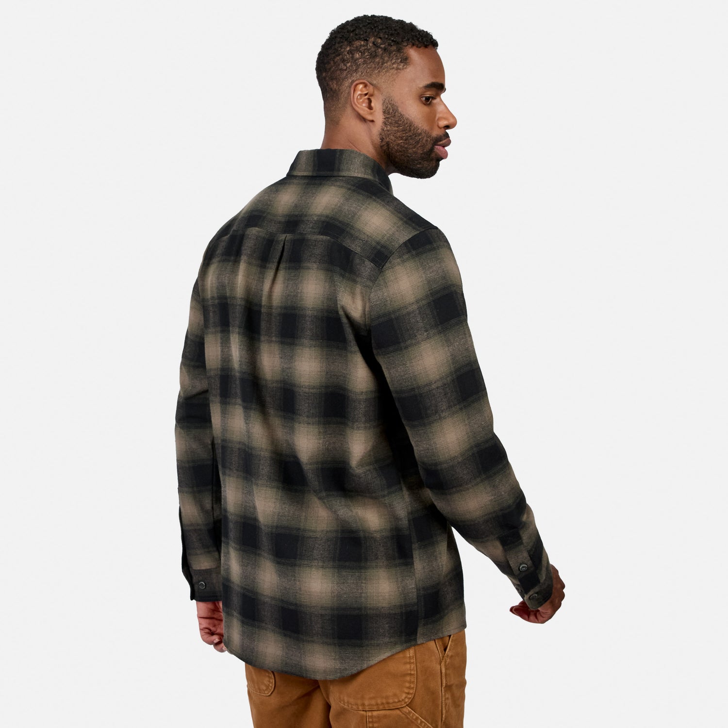 [Model is wearing size M.] A man wearing a dark brown and black plaid flannel shirt, shown from a three-quarters back view against a light gray background.