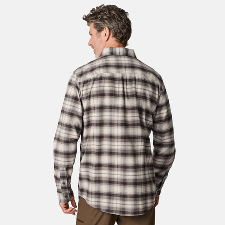 A man with short, curly hair is seen from the back wearing the Free Country Men's Easywear Flannel Shirt in black, gray, and white plaid made of lightweight fabric, paired with brown pants against a plain white background.
