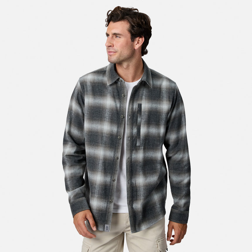 [Model is wearing size M.] A man wearing a dark gray and black plaid button-down shirt over a white t-shirt and beige pants, photographed against a light gray studio background.