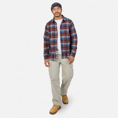 A man wearing a Free Country Men’s Easywear Flannel Shirt in blue and red plaid over a white t-shirt, paired with tan cargo pants and tan boots.