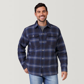 A man with short dark hair and a beard smiles while wearing the Clearance Men's FreeCycle® Utility Work Shirt over a gray t-shirt and light blue jeans, standing against a plain light gray background.
