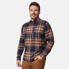 A man with short brown hair and a beard wears the Free Country Men's Easywear II Fleece Lined Flannel Shirt with brown pants. He stands against a white background, one hand in his pocket, smiling slightly.