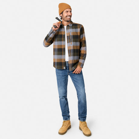 [Model is wearing size M.] A man modeling a brown and gray plaid flannel shirt, blue jeans, tan suede boots, and a tan beanie against a light gray background.