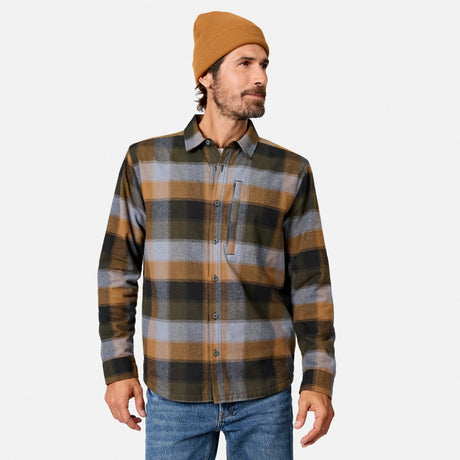 [Model is wearing size M.] A man wearing a brown, gray, and black plaid button-down flannel shirt, a tan beanie, and blue jeans, standing against a light gray studio background.
