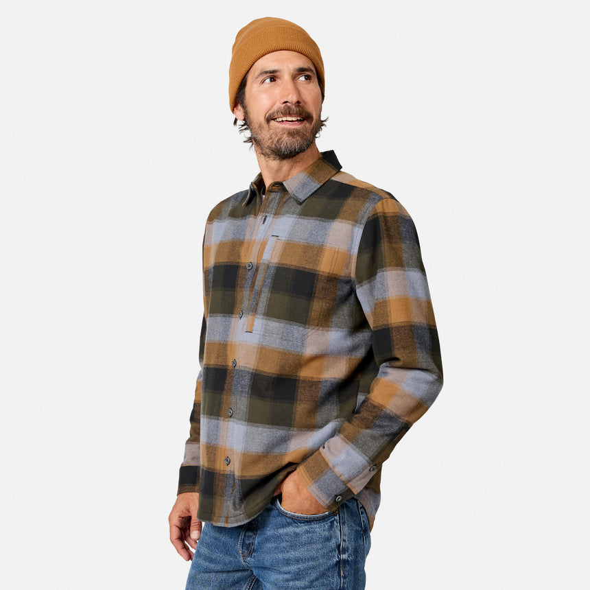 [Model is wearing size M.] A man wearing a brown and gray plaid button-down flannel shirt, a tan beanie, and blue jeans, standing against a light gray studio background.