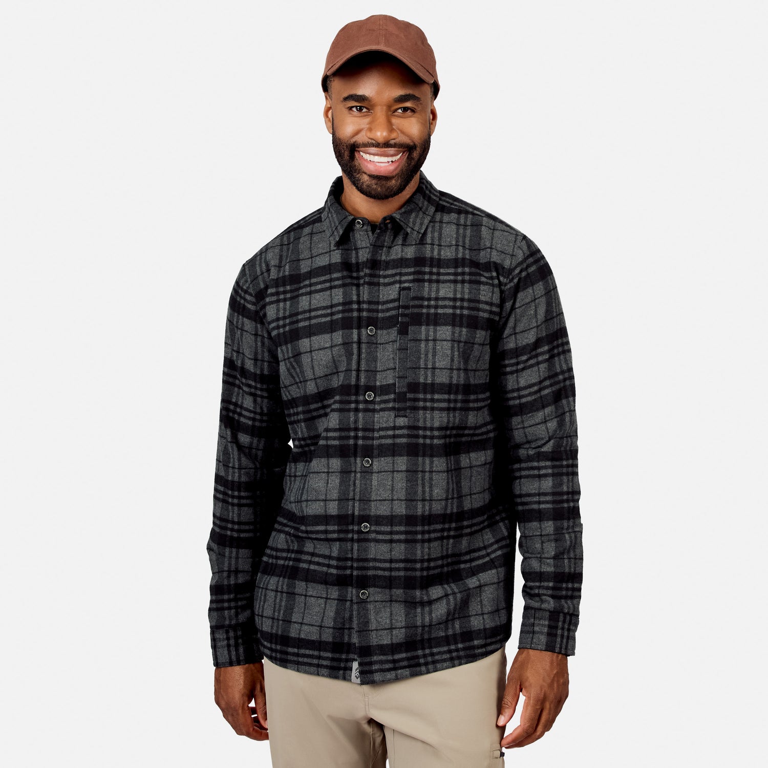 [Model is wearing size M.] A smiling man wearing a dark gray and black plaid button-down shirt, beige pants, and a brown baseball cap, photographed against a light gray studio background.