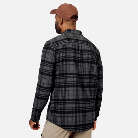 [Model is wearing size M.] A man wearing a dark gray and black plaid flannel shirt, viewed from the back. He is also wearing a brown baseball cap and khaki pants, set against a plain light gray background.