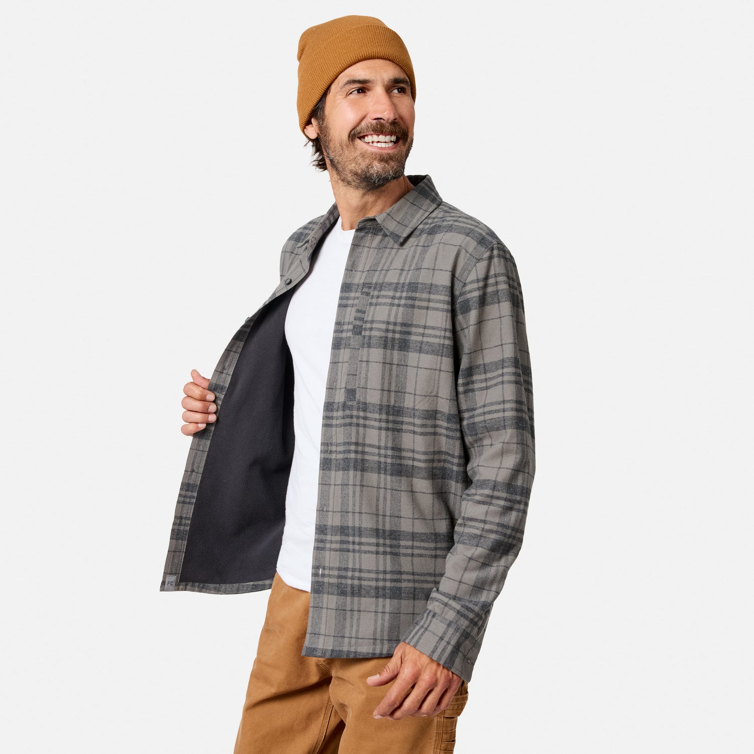 [Model is wearing size M.] A man wearing a gray and black plaid button-up shirt jacket over a white t-shirt, paired with a tan beanie and tan pants, shown against a light gray background.