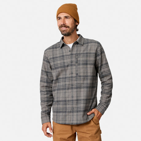 [Model is wearing size M.] A man wearing a gray and black plaid button-down shirt, a tan beanie, and tan pants, standing against a light gray studio background.