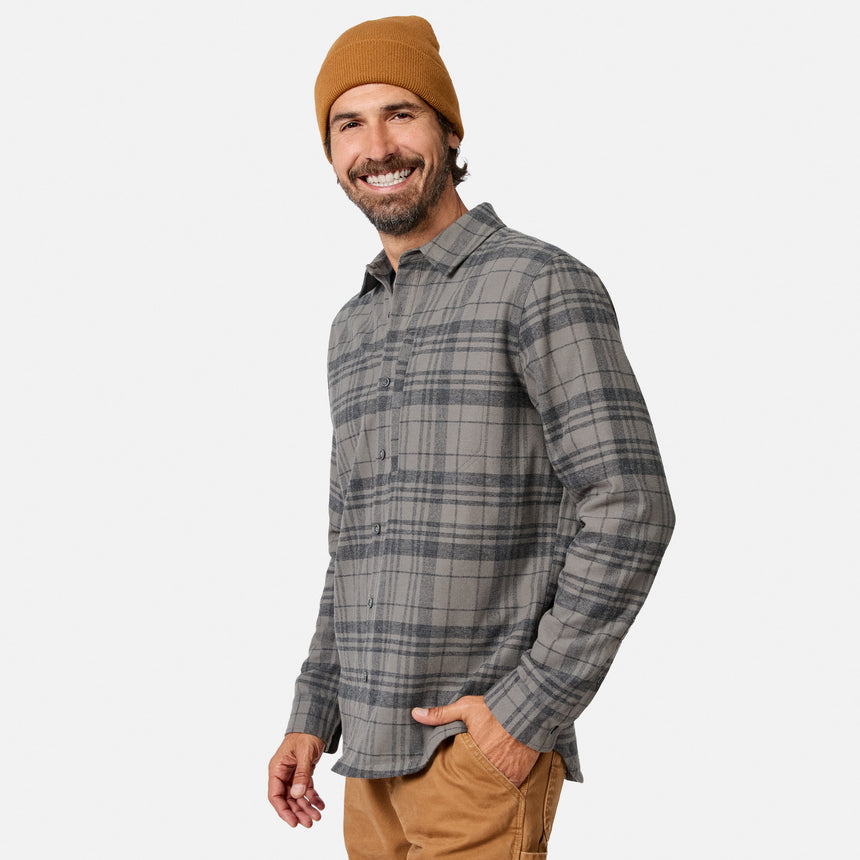 [Model is wearing size M.] A smiling man wearing a gray and black plaid button-down shirt, a tan beanie, and tan pants, photographed against a clean light gray studio background.