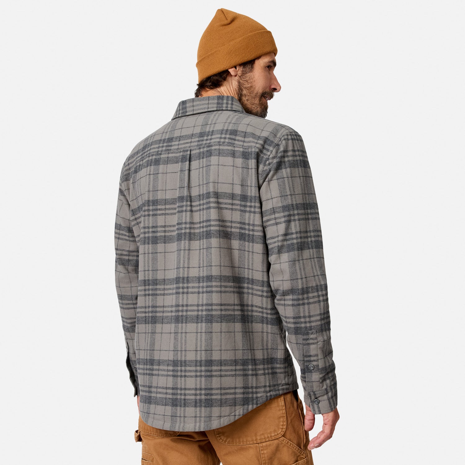 [Model is wearing size M.] A man wearing a gray and charcoal plaid flannel shirt, a mustard yellow beanie, and brown pants, shown from a back-three-quarter view against a light gray studio background.