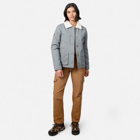 [Model is wearing size S.] A model stands against a light gray studio background wearing a light gray utility jacket with a cream sherpa collar, brown cargo pants, and brown hiking boots.
