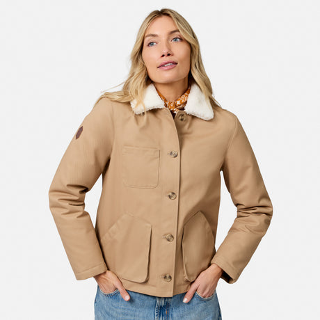 [Model is wearing size S.] A woman wearing a tan utility jacket with a white sherpa collar, paired with blue jeans and a chunky gold necklace, photographed against a light gray studio background.