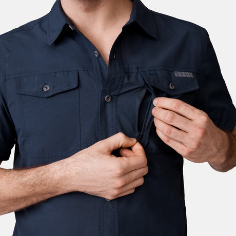 A man in the Clearance Men's Expedition Nylon Rip-Stop Short Sleeve Shirt unzips a hidden chest pocket for discreet storage; the shirt also features two buttoned chest pockets.