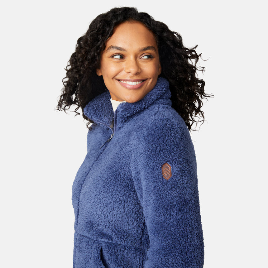 Woman wearing a blue fleece jacket with a brand logo on a white background