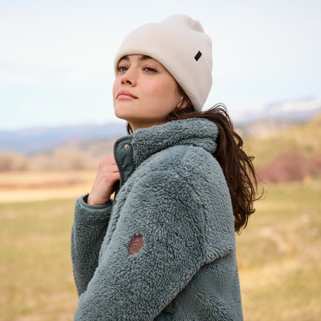 Person wearing a green fleece jacket and white beanie in an outdoor setting