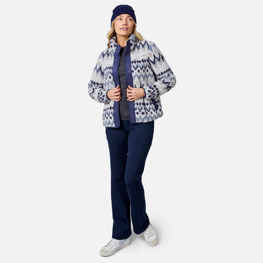 [Model is wearing size S.] A woman modeling a patterned zip-up fleece jacket, navy pants, a navy beanie, and white sneakers against a light gray studio background.