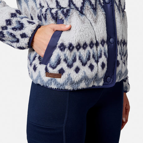 [Model is wearing size S.] Close-up of a person wearing a fuzzy fleece jacket with a navy blue and white geometric pattern, paired with dark navy leggings. The jacket has a brown leather brand patch on the lower front pocket.