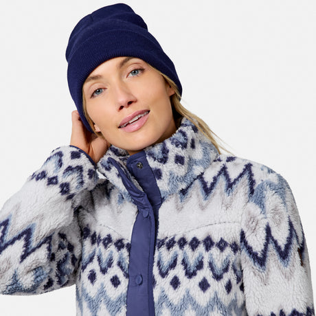 [Model is wearing size S.] A woman wearing a navy blue knit beanie and a fuzzy zip-front fleece jacket with a blue and white geometric pattern, photographed against a light gray studio background.