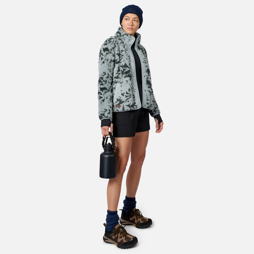 [Model is wearing size S.] A woman modeling a light gray and dark gray patterned fleece jacket, black athletic shorts, a navy beanie, and hiking boots, holding a black water bottle against a light gray background.