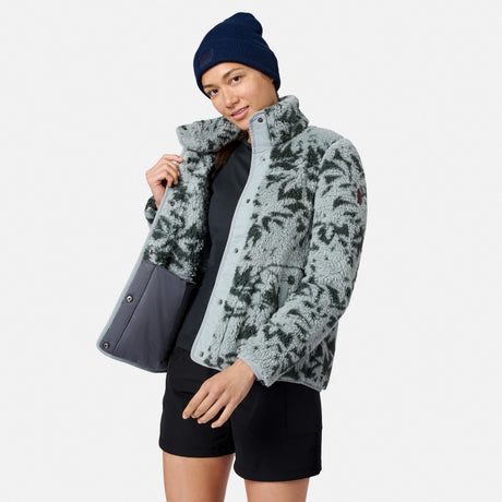 [Model is wearing size S.] A woman modeling a light gray fleece jacket with a dark gray abstract pattern, a dark gray inner lining, a navy blue beanie, and black shorts against a light gray background.