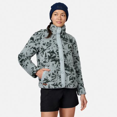 [Model is wearing size S.] A woman modeling a light gray and black patterned fleece jacket with a high collar, paired with black shorts and a navy blue beanie, against a light gray studio background.