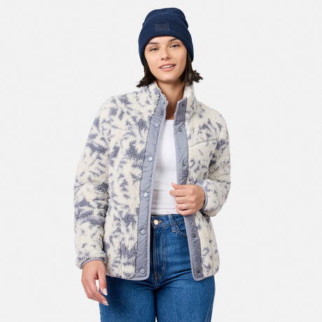 [Model is wearing size S.] A woman modeling a fuzzy sherpa-style jacket with a gray and off-white abstract pattern, paired with a navy beanie, white top, and blue jeans against a light gray studio background.