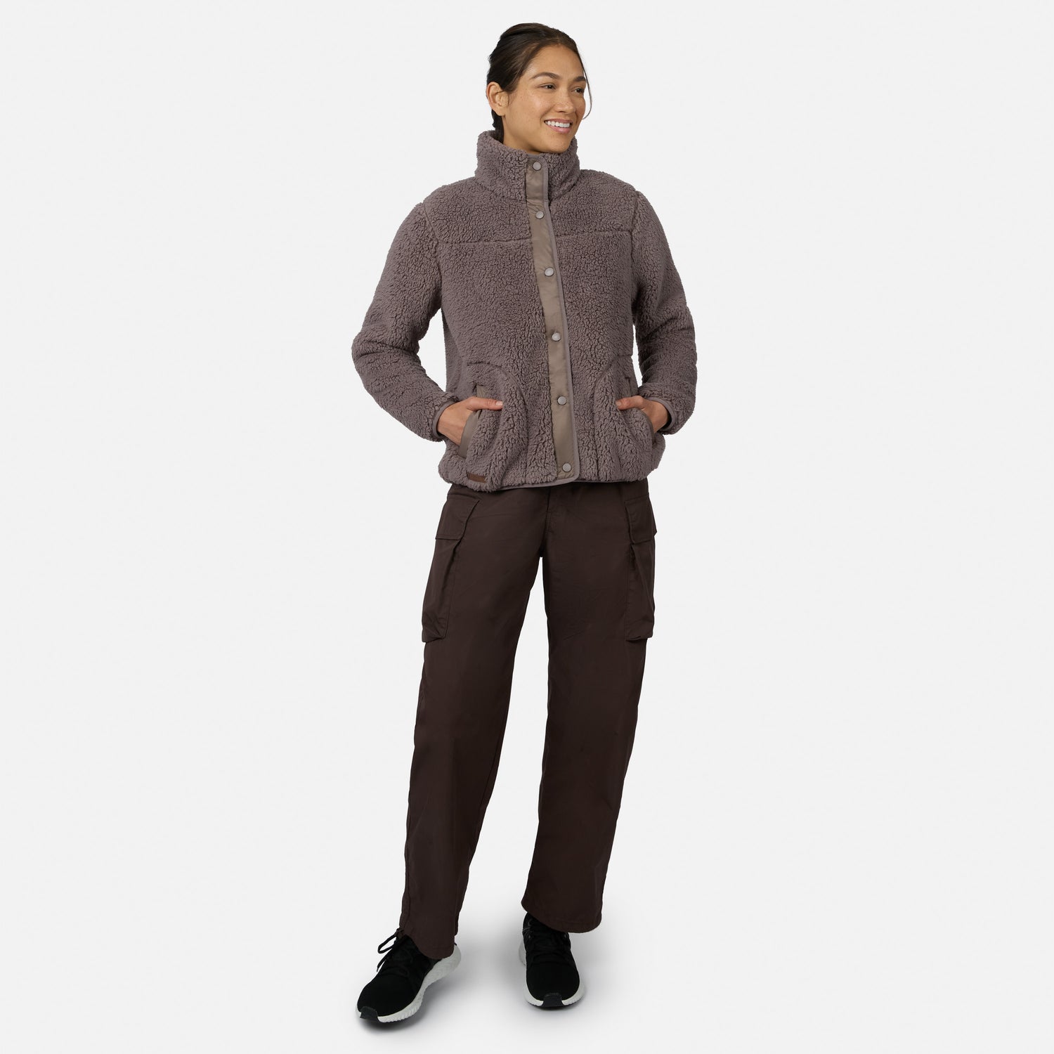 [Model is wearing size S.] A woman modeling a heathered taupe fleece button-up jacket with a high collar and side pockets, paired with dark brown cargo pants and black sneakers, against a light gray background.