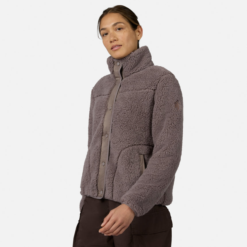 [Model is wearing size S.] A woman wearing a taupe-brown sherpa fleece button-up jacket with a high collar, shown from the waist up against a light gray studio background.