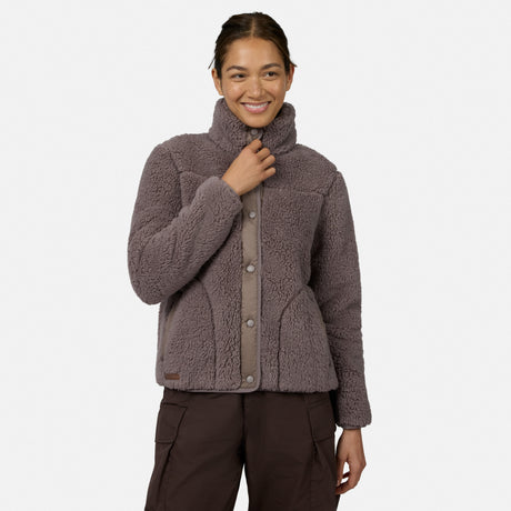 [Model is wearing size S.] A woman wearing a taupe-brown sherpa fleece button-front jacket with a high mock neck collar, paired with dark brown cargo pants, against a light gray studio background.