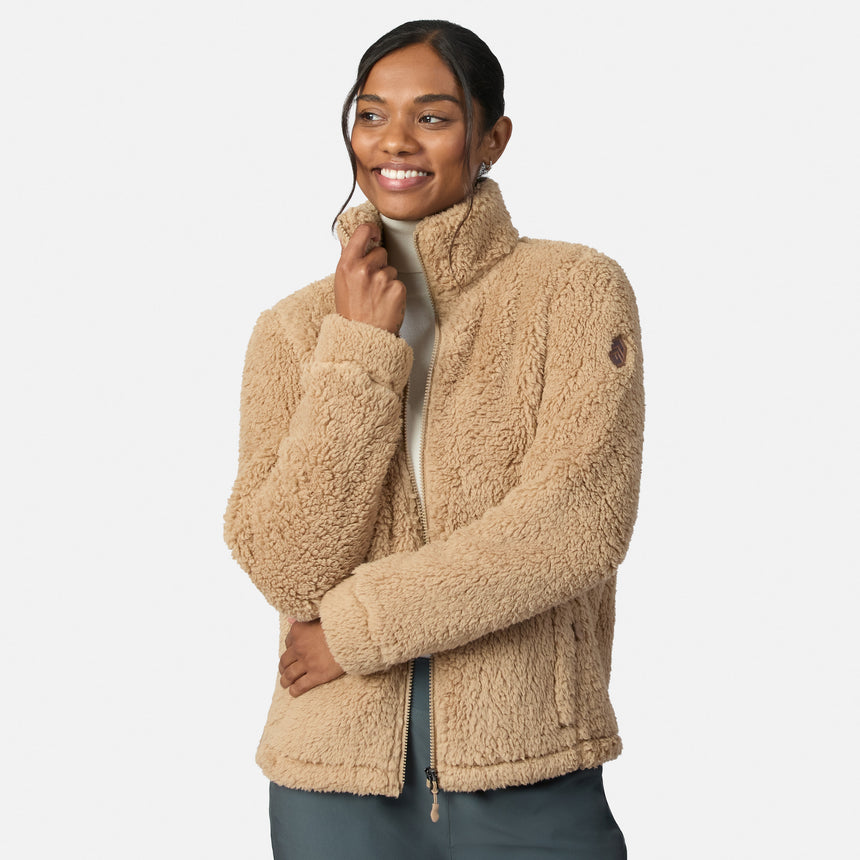 A woman in the Free Country Women’s Sierra Butter Pile® Zip Up Jacket smiles, hand on her chin, against a white background, radiating cozy warmth and style.